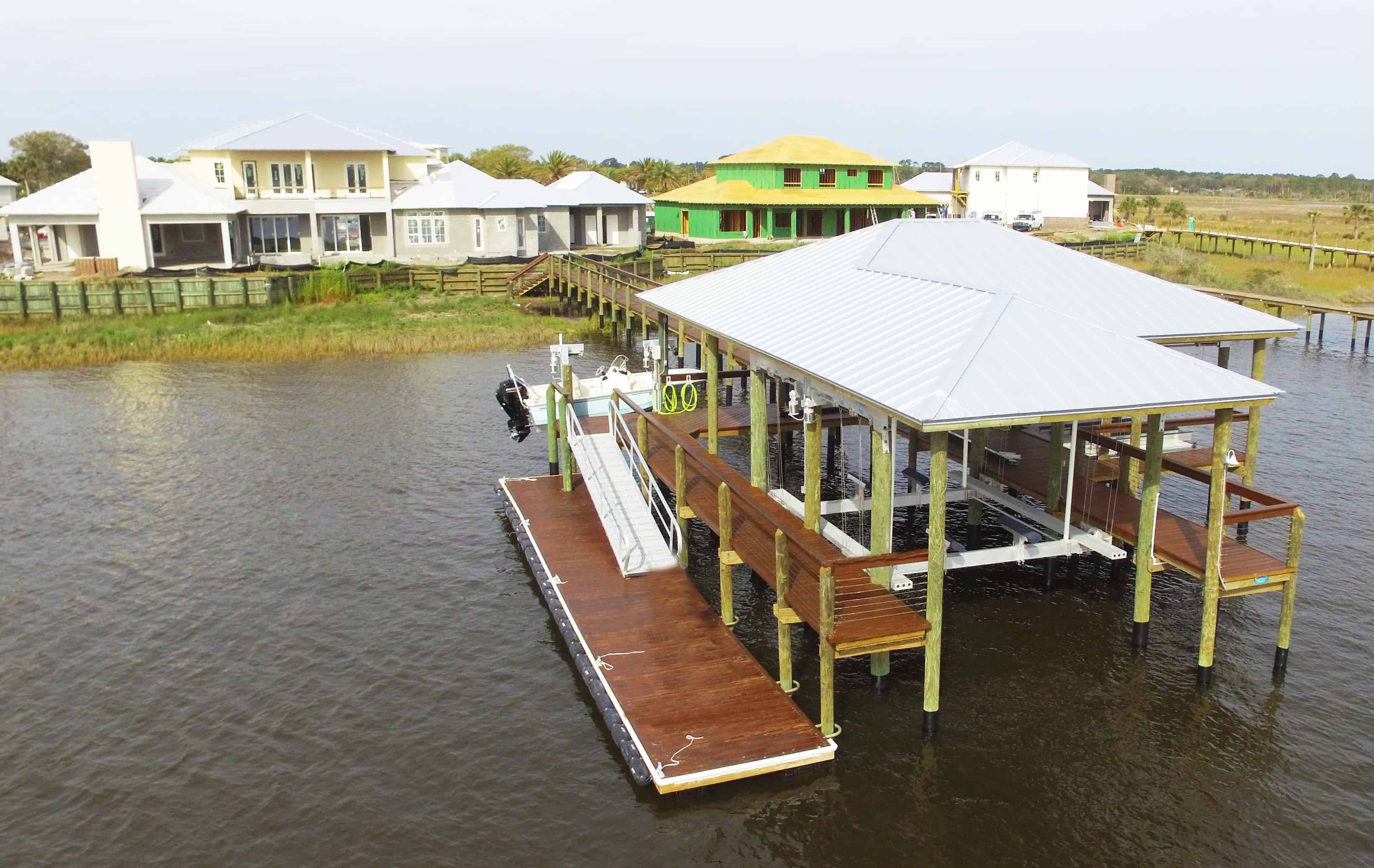 Aerial view of a boathouse with a long approach dock over shallow water