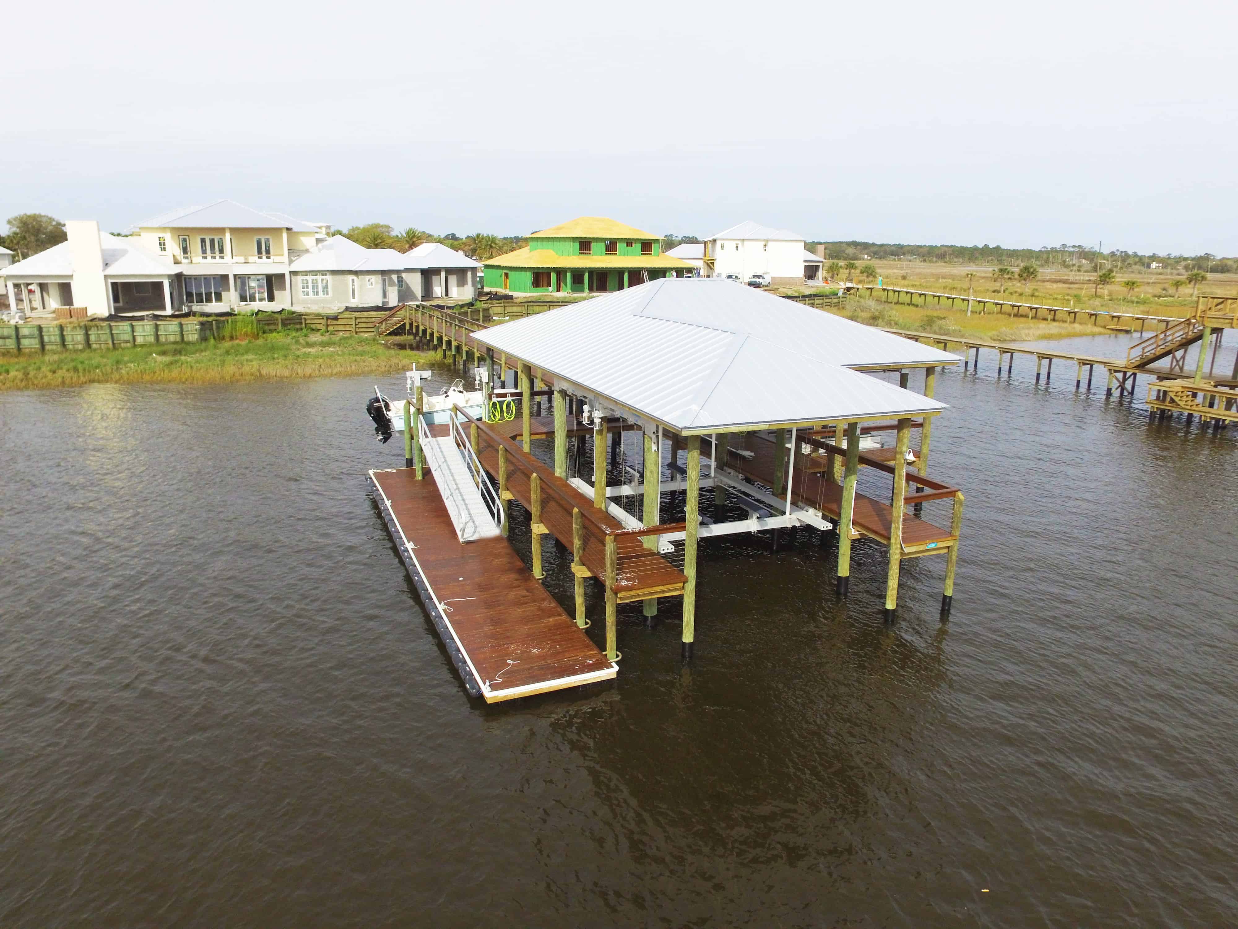 Aerial view of a white-roofed boathouse and dock over marsh