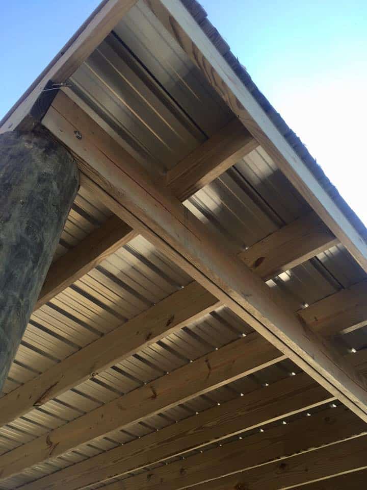 Underside of a new dock roof showing wood rafters and white metal panels against blue sky