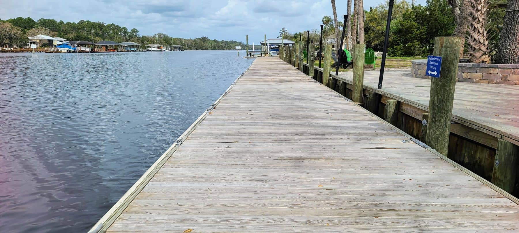Weathered timber dock walkway running out over calm water