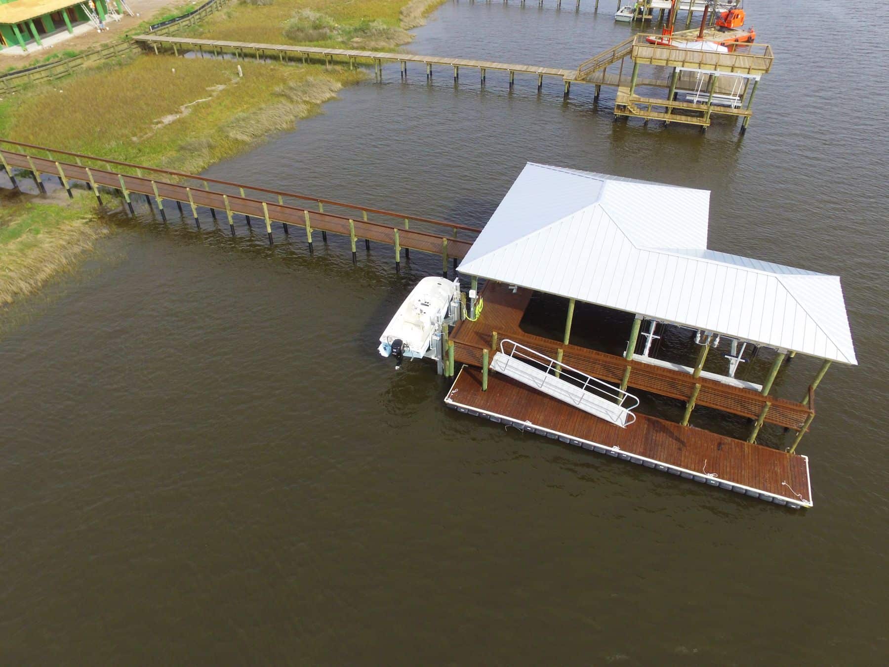 Aerial view of a boathouse with white roof and timber walkway