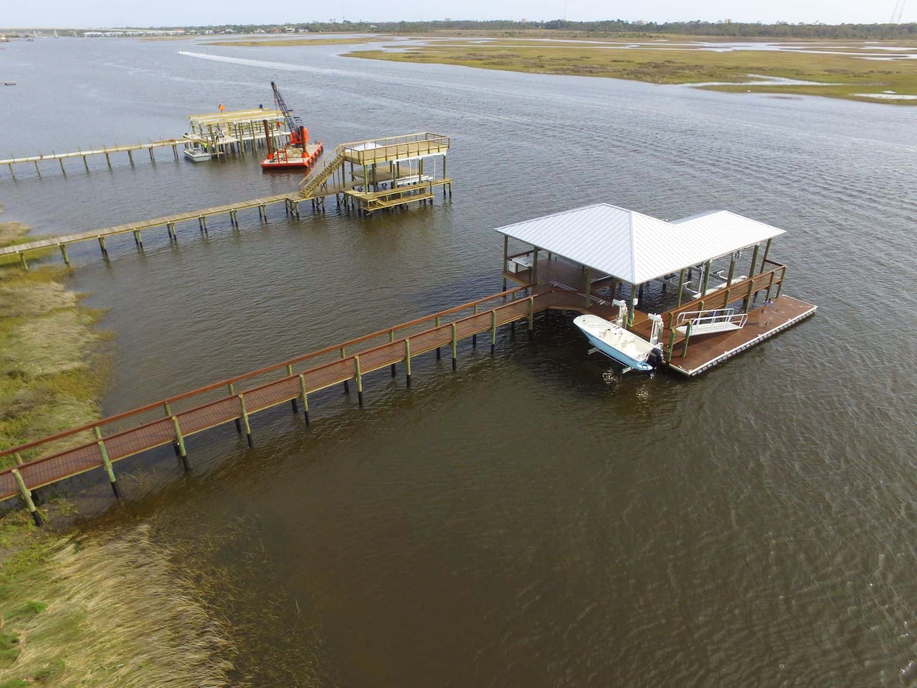 Aerial view of a long dock crossing shallow water to a covered berth
