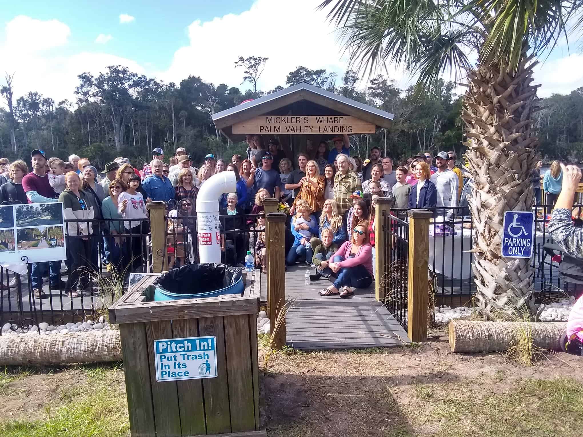 Large crowd posing at the Mickler's Wharf pavilion behind a fenced dock entrance ramp